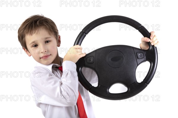 Funny little boy holding a car steering wheel. Young driver on a white background