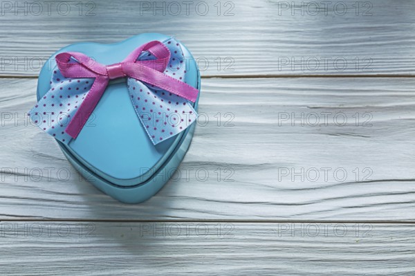 Heart-shaped blue gift box with pink bow on wooden board holidays concept