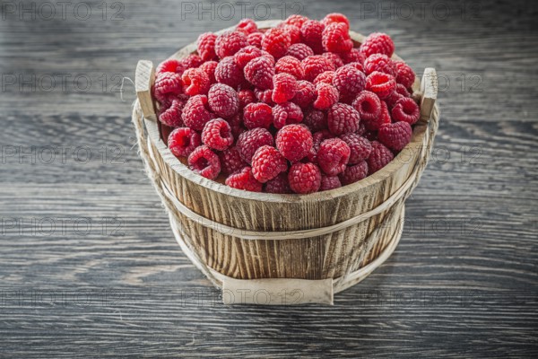 Raspberries in bucket on wooden board