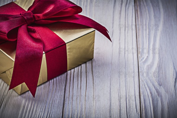 Present box with red ribbon on wooden board holidays concept