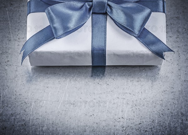 Present box with blue ribbon on metallic background celebrations concept