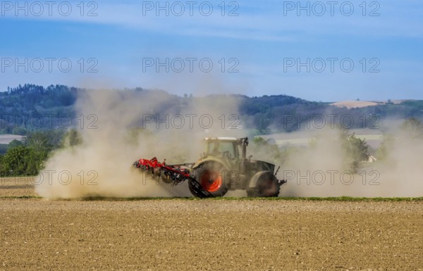 A farmer cultivates his parched field with a tractor during a dry period. Austria, Upper Austria, Eferding district