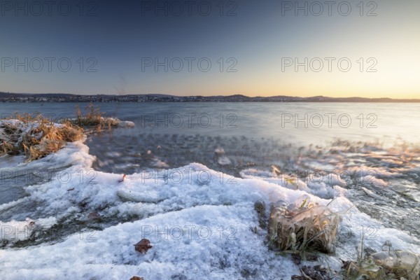 Snow-covered lakeshore with gentle waves at sunrise, Niederzell, Reichenau, Lake Constance, Baden-Württemberg, Germany, Europe