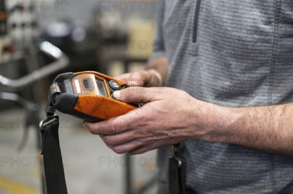 Factory worker. Technician controlling a heavy crane in factory, close up at his hands holding a crane controller.