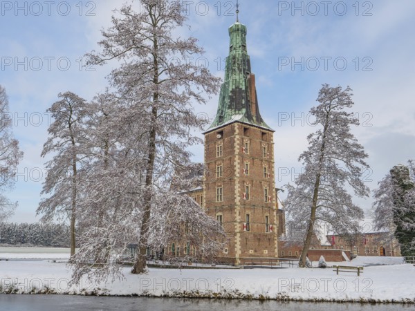 Historic castle tower on the lake in winter with snow-covered trees and a clear sky, Raesfeld, münsterland, germany