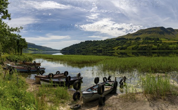 Glencar, Ireland, 16 July, 2022: Glencar Lough landscape with many colorful small wooden fishing boats on the lakeside, Europe