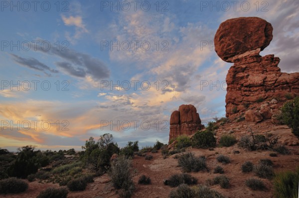 A colorful sunset glows over Balanced Rock, Arches National Park, Utah, USA, North America