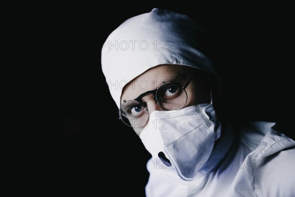 A medical professional wearing a mask and glasses in dark
