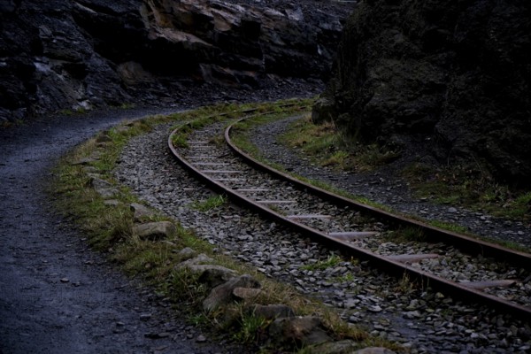 Abandoned railway line in a curve next to a narrow path through a rocky landscape, Piesberg 49134 Wallenhorst, Germany, Europe