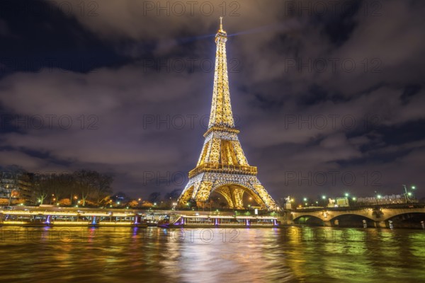 Paris, France, February 14, 2016: The Eiffel Tower golden lights, at night, reflected in the Seine River water in Paris, France on February 14, 2016, Europe