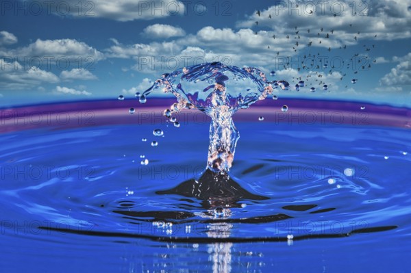 A splashing drop of water in front of a sky with white clouds and flying birds, highspeed photography, drop photography, composing, Grenzach- Wyhlen, Baden-Württemberg, Germany, Europe