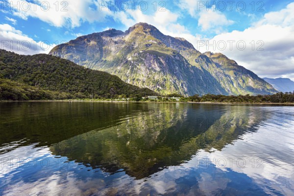 The mountains are reflected in the smooth water of the fjord. The most famous and picturesque fjord is Milford Sound, of glacial origin. Fiordland park. New Zealand. South Island