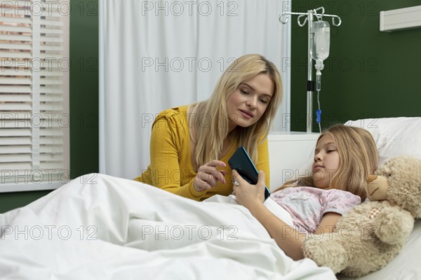 In a heartfelt hospital moment, a woman and a girl share a phone, reinforcing their connection in a challenging time