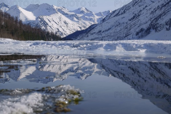 Winter landscape with mountain lake and high mountains reflected