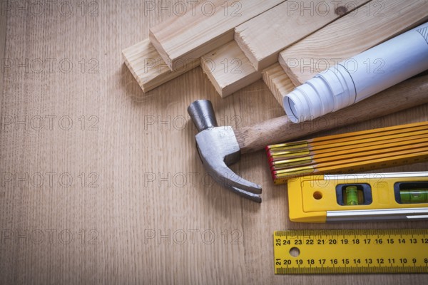 Wooden studs and meter ruler hammer blueprints construction level on wood background building and architecture concept