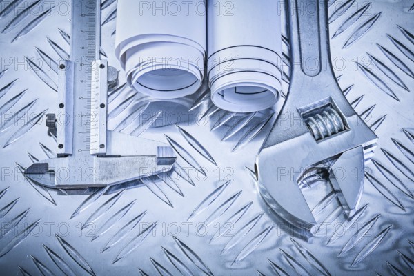 Construction plans vernier caliper adjustable wrench on grooved metal sheet maintenance concept