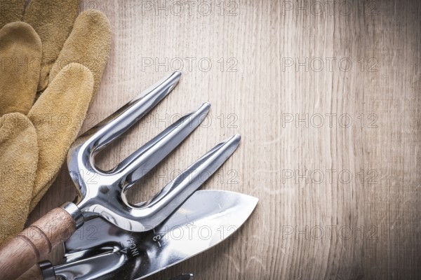 Steel trowel fork with shovel and leather safety gloves on wooden background copyspace image agriculture concept