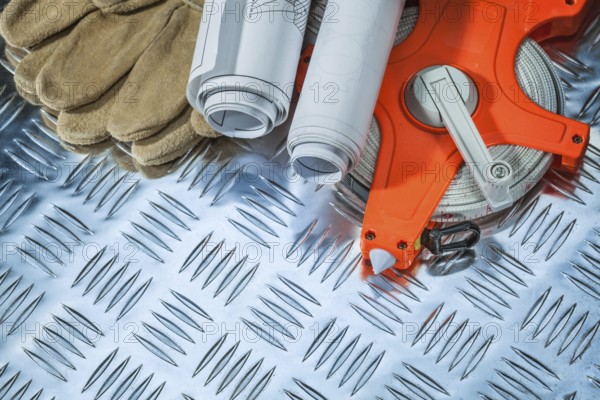 Protective gloves tape measure construction drawings on corrugated metal plate