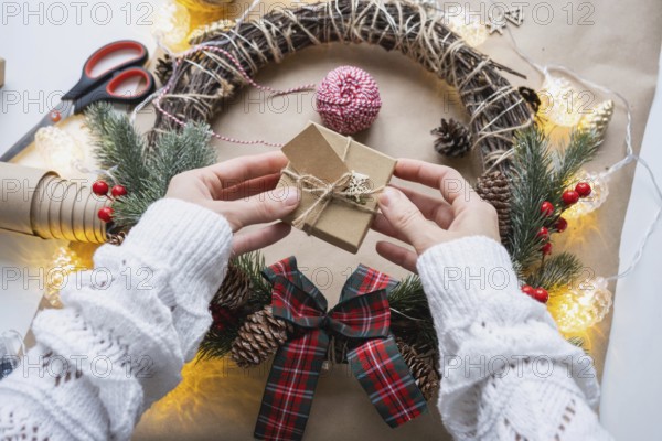 Pack a gift for Christmas and new year in kraft paper, cones, tape, scissors. Tags with mock up, natural decor, hand made, DIY. Festive mood. Flatlay, background