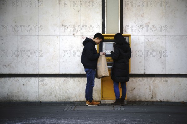 Frankfurt, Germany - January 05, 2017: Two young Asian tourists stand at a stamp vending machine at Frankfurt Airport on 5 January 2017 in Frankfurt, Germany, Europe