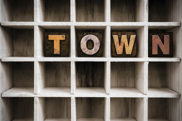 The word TOWN written in vintage ink stained wooden letterpress type in a partitioned printer's drawer
