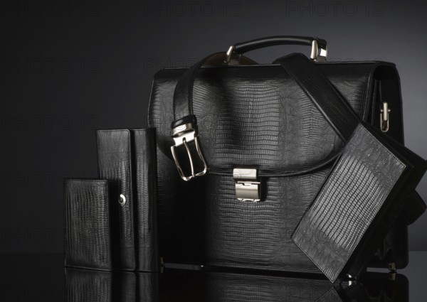 Fashionable men's set of leather accessories on a dark background. Briefcase, wallet, belt