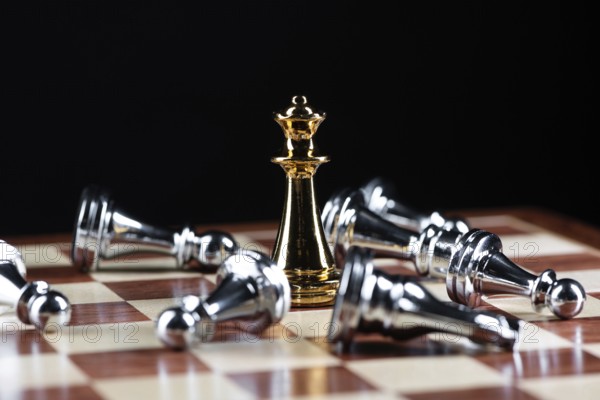 Gold queen chess defeats silver figures on wooden chessboard. Intellectual duel and tactical battle in business. Strategy planning, leadership and teamwork. Checkmate and winning in game concept