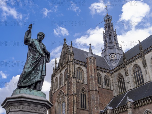 Monument to the Dutch inventor of letterpress printing Laurens Janszoon Coster on the Grote Markt and in the background the St. Bavo Cathedral (De Grote of St. Bavokerk te Haarlem) in the centre of the old town, Haarlem, North Holland, Netherlands