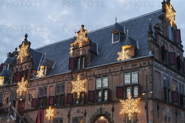 Old building with Christmas decorations and stars on the roof under a cloudy sky, nijmegen, the netherlands