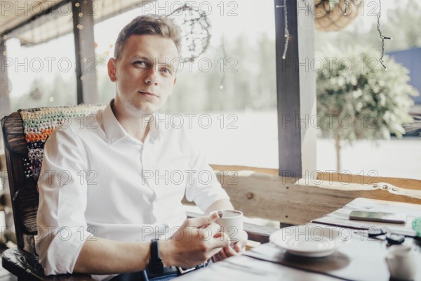 Man enjoying a cup of coffee on a patio, ambient light surrounding him