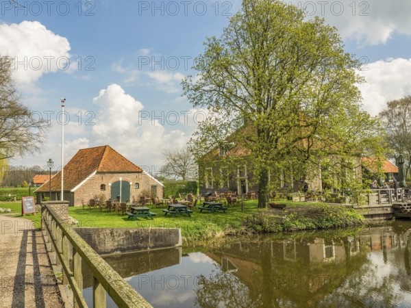 Rural scene with several buildings, a large tree and a small bridge crossing a river, Eibergen, Gelderland, Netherlands