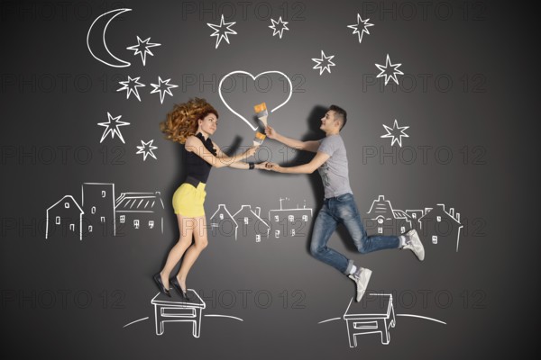 Happy valentines love story concept of a romantic couple standing on a stool and painting a heart in the night sky against chalk drawings background
