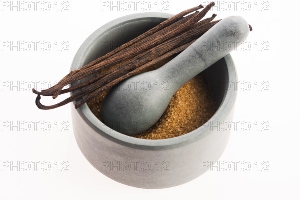Brown vanilla sugar and vanilla beans in mortar