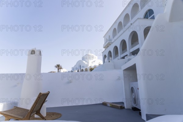 Deckchair on a viewpoint of a hotel complex, white buildings, orthodox cathedral in the background, Fira, Santorini island, Greece, Europe