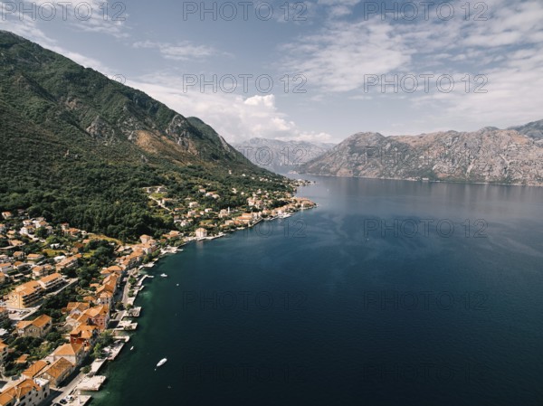 Red roofs of houses with private piers on the shores of the Bay of Kotor. Dobrota, Montenegro. Drone.