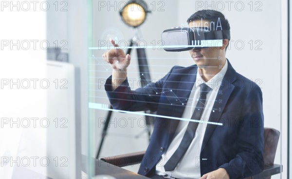 Asiatische Geschäftsmann mit virtueller Realität goggle und zeigt Geschäftswachstum Chart in einem Büro