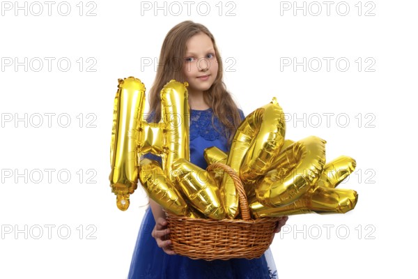 Little girl in a festive blue dress holds a golden set of happy birthday inflatable letters. Isolated on a white background