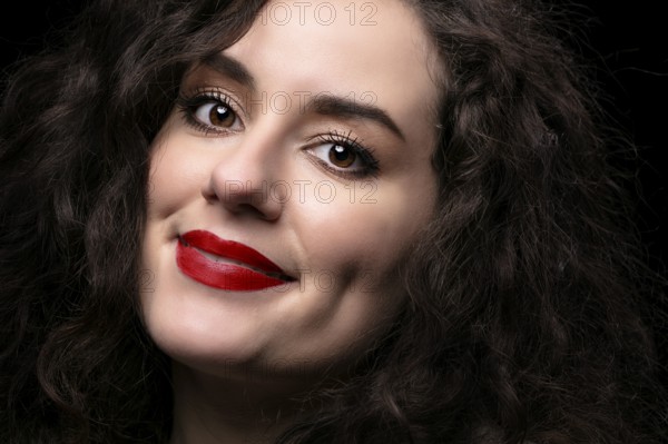 Portrait of a beautiful brunette girl with curly hair and red lipstick