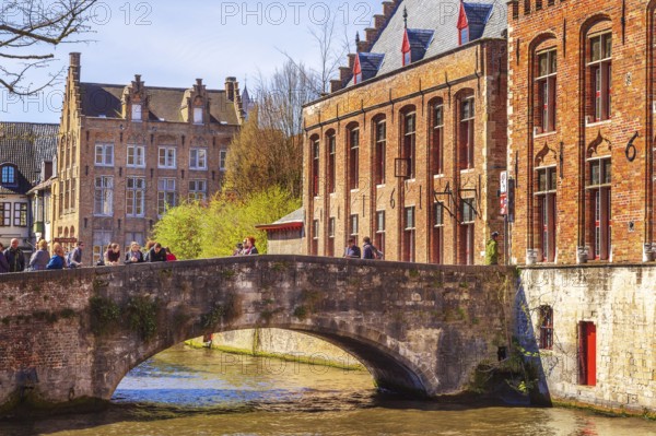 Bruges, Belgium, April 10, 2016: Scenic cityscape with houses, people on bridge and canal in Bruges, Belgium, Europe