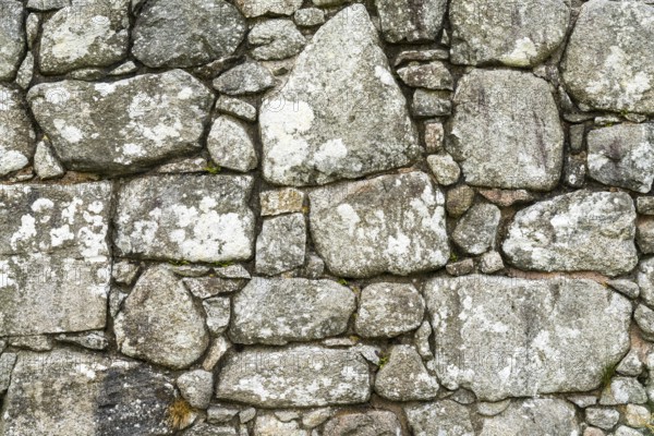 A background of an old stone wall built with uneven and random blocks and stones