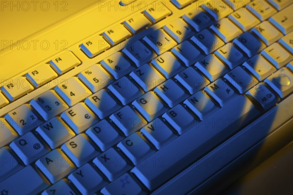 Computer keyboard and the shadow of a hand. Theft of data. Austria