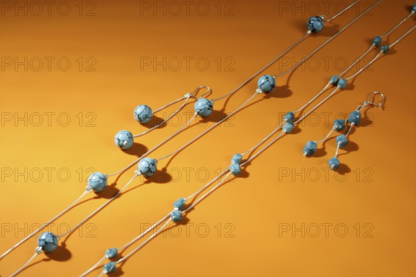 Turquoise necklaces over orange background, selective focus