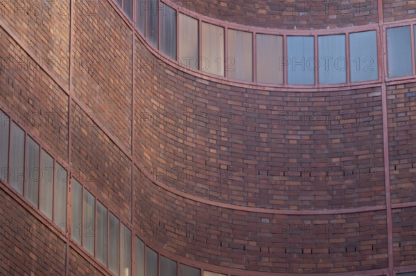 Curved brick wall section of a building with aligned windows