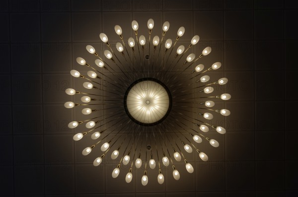 Large luxurious chandelier with burning bulbs seen from below