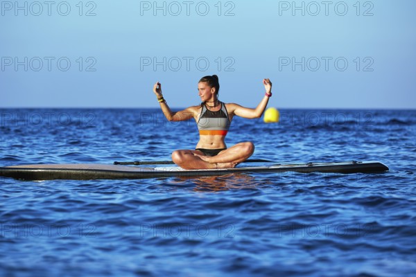 Yoga girl over SUP Stand up Surf board at the ocean sea