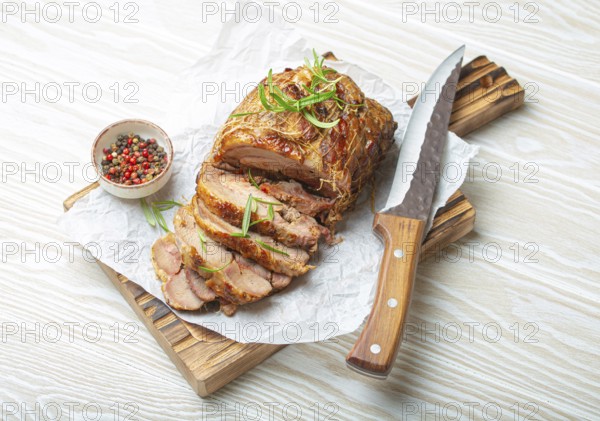 Rolled turkey roasted with spices and herbs on baking paper with knife and wooden white background top view. Baked cut for slices turkey fillet roll for dinner, food photography, food photography