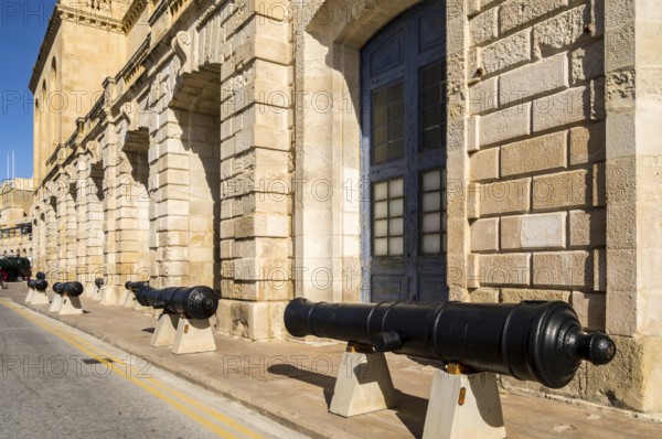 Old cannons lined up in front of the facade of the marine museum in Malta