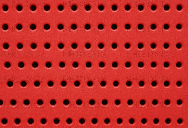 Red perforated plastic background closeup