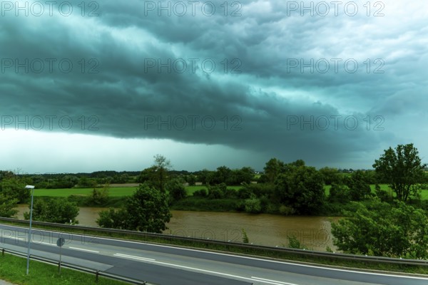 Threatening cloud formation over a road and a river in green surroundings, Bogen, Lower Bavaria