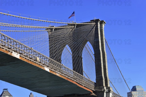 Brooklyn Bridge in Brooklyn, Manhattan, New York, section of a bridge with waving American flag and clear blue sky, New York City, USA, North America